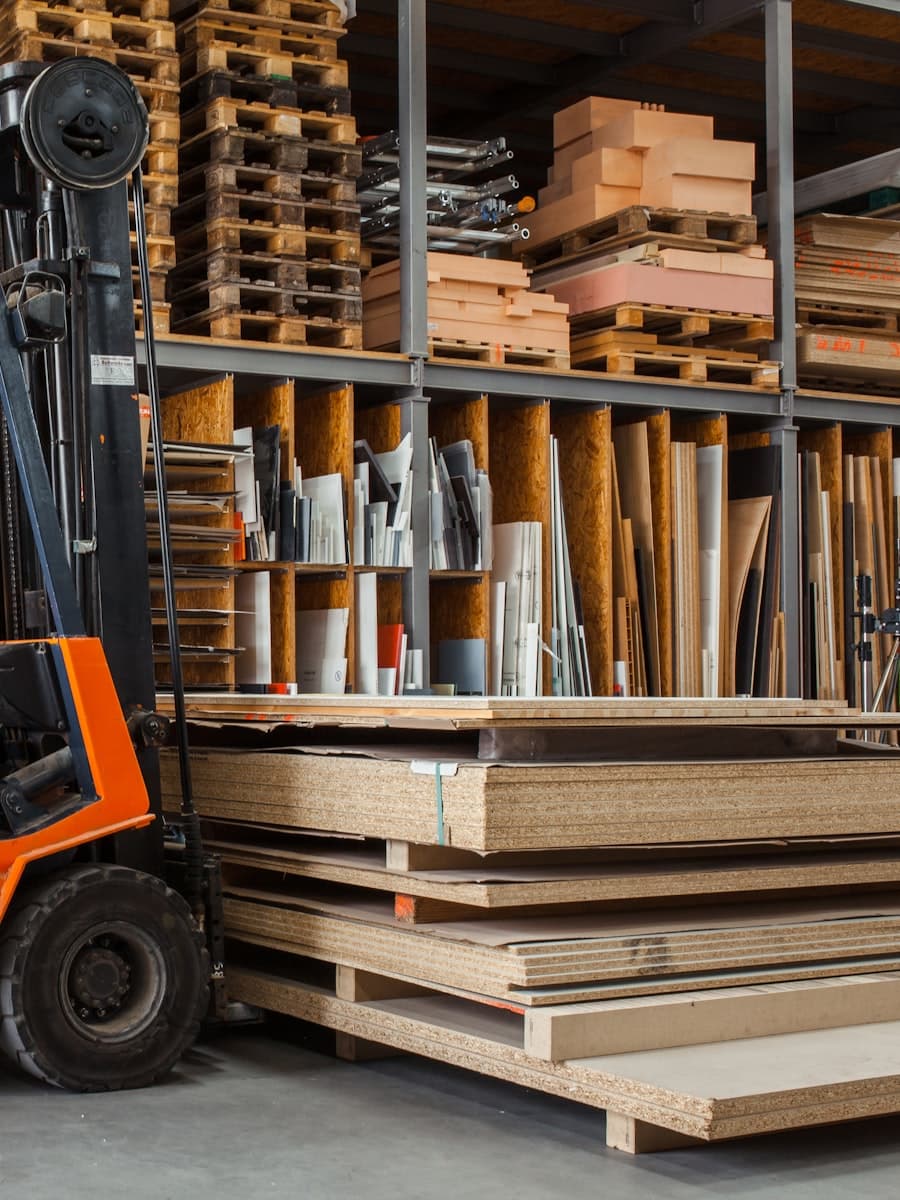A forklift beside pallets and stacked board stock in a warehouse